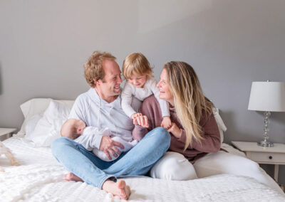 A Young family snuggled up and have a great time laughing. Toddler brother and being silly while dad is holding their newborn baby.